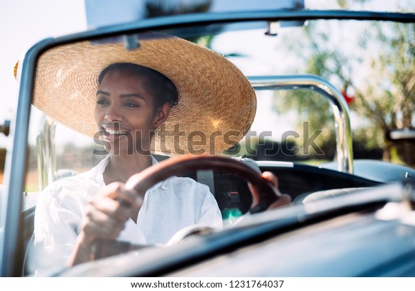 Black woman
driving a vintage convertible
car
