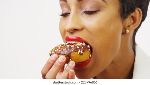 Black Woman Eating Chocolate Donut With Sprinkles And Smiling