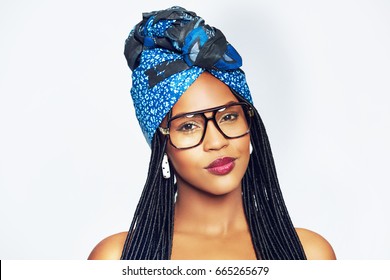 Black Woman With Ethnic Head Wrap And Traditional Bunches Hairstyle Wearing Glasses And Looking At Camera.