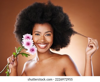 Black woman, flowers and natural beauty,  hair and glowing skincare, organic makeup or eco dermatology on studio background. Portrait happy african model, curly hair and pink daisy blossom plants