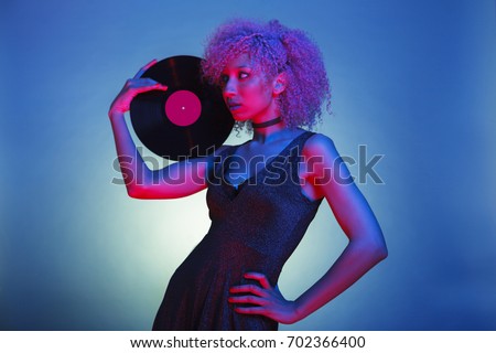 black woman with groovy hair holding an old eighties vinyl with retro disco lights