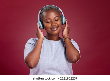 Black woman, headphones and smile for music listening, streaming or relax against a studio background. African American female with smile enjoying audio track, hifi or relaxing with wireless headset - Powered by Shutterstock