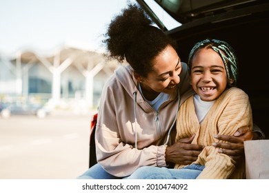 Black Woman And Her Daughter Laughing And Hugging While Sitting In Car Trunk