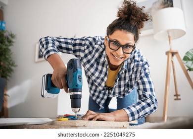 Black woman holding electric drill tool to assembly furniture in new home - Powered by Shutterstock