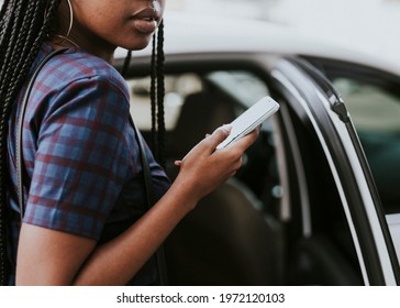 Black Woman Holding Her Phone While Getting Into A Car