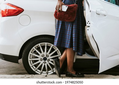 Black Woman Holding Her Phone While Getting Into A Car