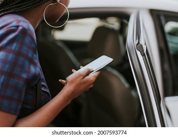 Black Woman Holding Her Phone While Getting Into A Car