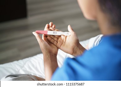 Black woman holding positive pregnancy test. Close-up of hands and kit