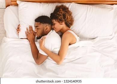 Black woman hugging her man and smiling, enjoying sleep together in bed, top view with empty space - Powered by Shutterstock
