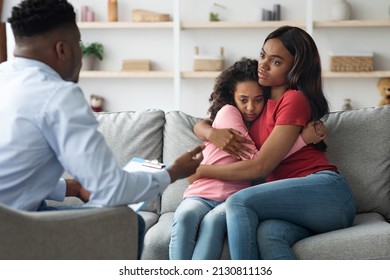 Black Woman Hugging Her Scared Daughter While Attending Child Psychologist, African American Mother And Child Teenager Having Therapy Session With Male Psychotherapist. PTSD In Children