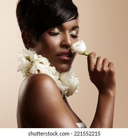 Black Woman With Ideal Skin And Closed Eyes Sniffing A Flower