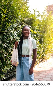 Black Woman With Mesh Bag Of Fruits Walking In The City.