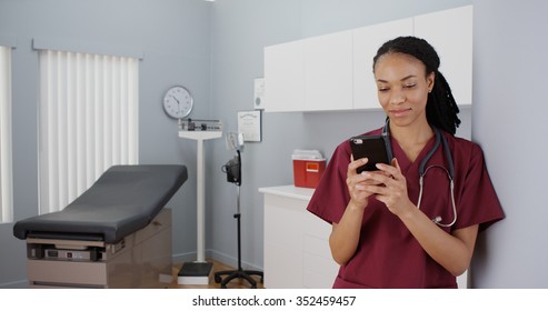 Black Woman Nurse Texting On Smartphone