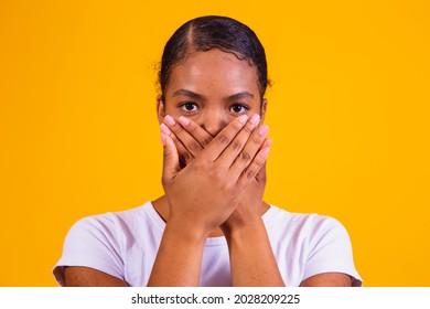 black woman on yellow background with her mouth closed in silence. Concept of prejudice, abuse and racism