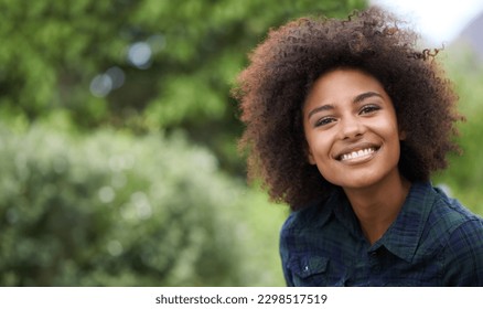 Black woman outdoor in portrait, smile in nature with positive mindset with mockup space. Headshot of happy female person, young and carefree with curly afro hairstyle and happiness at the park - Powered by Shutterstock