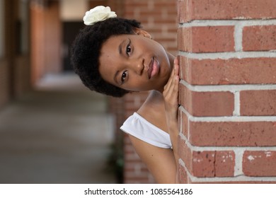 Black Woman Peeking Around A Brick Pillar