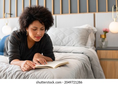 Black Woman Reading Book And Lying In Bed