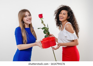 Black Woman Receiving Heart Shaped Valentine Gift And Rose From Girlfriend Isolated On White