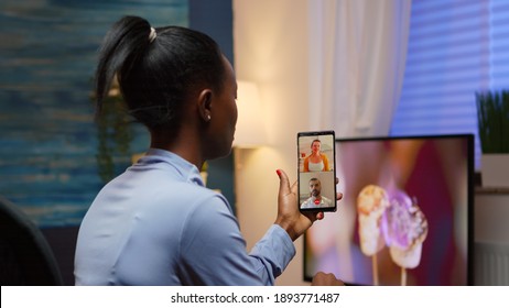 Black Woman Remote Entrepreneur Having Video Conference With Friend Using Smartphone Sitting In Living Room Late At Night. Busy Employee Using Modern Technology Network Wireless Doing Overtime For Job