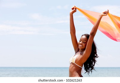 Black woman with a sarong at the beach feeling the wind