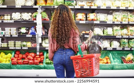 Black woman, shopping groceries and vegetables in store with flowers on sale choice, discount or valentines promotion. Young female person, vegan food or decide by shelf for product in grocery basket