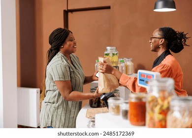 Black woman shops for fresh organic produce at local store. Customer purchasing nutritious bio food products from eco friendly shop, taking grocery bag from vendor at checkout counter. - Powered by Shutterstock