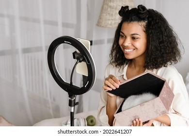 Black Woman Showing Box While Taking Selfie Footage On Cellphone At Home