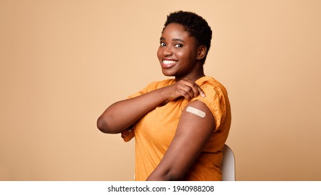 Black Woman Showing Vaccinated Arm After Vaccine Injection, Beige Background