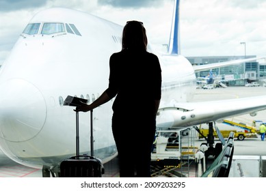 Black woman silhouette looking to aircraft in the airport hall- missed or cancelled flight concept. broken aircraft or catastrophe concept.