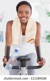 Black Woman Sitting On An Exercise Bike In A Living Room