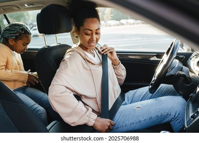 Black Woman Smiling And Wearing Seat Belt While Sitting With Her Daughter In Car