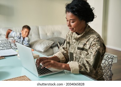 Black Woman Soldier Using Laptop At Home