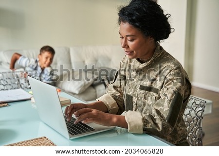 Black woman soldier using laptop at home