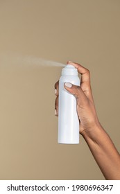 Black woman spraying an unlabeled spray bottle