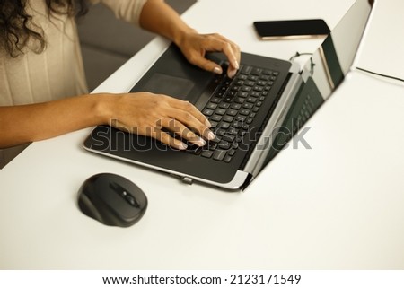 Black woman typing on laptop. Young African female working at home on notebook pc. Freelancer person doing distant work on lockdown. Free lance writer writing text on modern computer