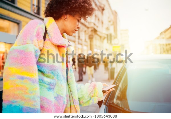 Black woman unlocking car sharing using\
smartphone - Woman opening car keyless - sharing, transportation,\
technology concept