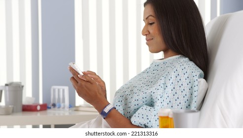 Black Woman Using Smart Phone In Hospital Bed