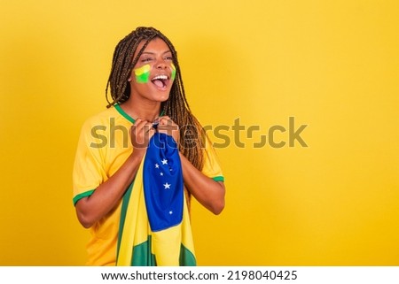 black woman young brazilian soccer fan. holding brazil flag, anxious, watching the match.