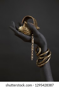 Black Woman's Hand With Gold Jewelry. Oriental Bracelets On A Black Painted Hand. Gold Jewelry And Luxury Accessories On Black Background Closeup. High Fashion Art Concept 