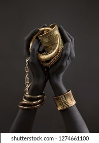 Black Woman's Hands With Gold Jewelry. Oriental Bracelets On A Black Painted Hand. Gold Jewelry And Luxury Accessories On Black Background Closeup. High Fashion Art Concept 