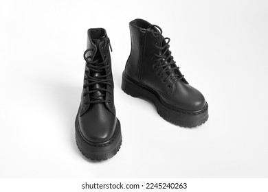 Black women combat boots on high heel platform with lug soles on isolated white background. Military stylish high heel platform combat boots for woman legs, new footwear trends