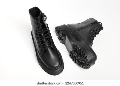 Black women combat boots on high heel platform with lug soles lying on isolated white background. Military stylish high heel platform combat boots for woman legs, new footwear trends