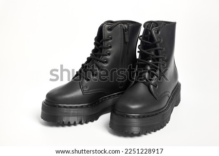 Black women combat boots on high heel platform with lug soles on isolated white background, top angle view. Military stylish high heel platform combat boots for woman legs, new footwear trends
