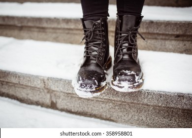 Black women's shoes on the stone steps covered by snow in the winter.