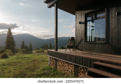 Black wooden chairs on cabin terrace with mountain view at sunset
