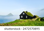 Black wooden faroese house with turf-top grass roof in the Velbastadur village on Streymoy island, Faroe islands, Denmark. Landscape photography