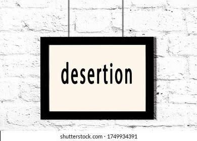 Black Wooden Frame With Inscription Desertion Hanging On White Brick Wall 