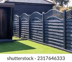 Black wooden garden fence with a fancy trellis