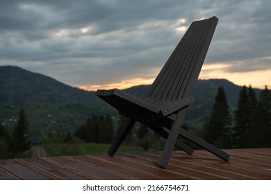 Black Wooden Patio Chair On Terrace With Mountain View At Sunset