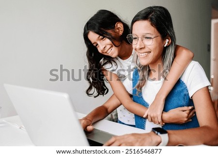 Black working mother using computer laptop at home office. Happy daughter hugging mom. Family love relationship